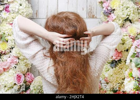 Frau steht vor der Tür mit romantischem Blumenschmuck mit Rosen-, Dahlia-, Hortensien- und Nelkenblumen. Stockfoto