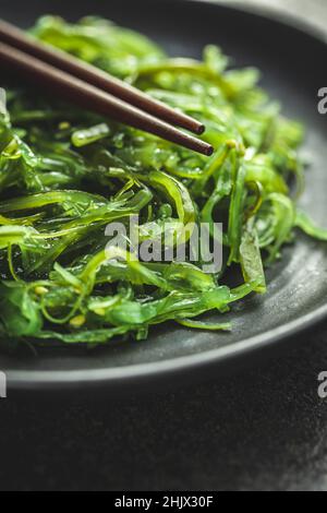 Grüner Wakame. Algensalat auf schwarzem Teller. Stockfoto