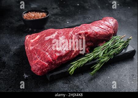 Rohes amerikanisches Tri Tip Beef Steak auf Marmorplatte. Schwarzer Hintergrund. Draufsicht Stockfoto