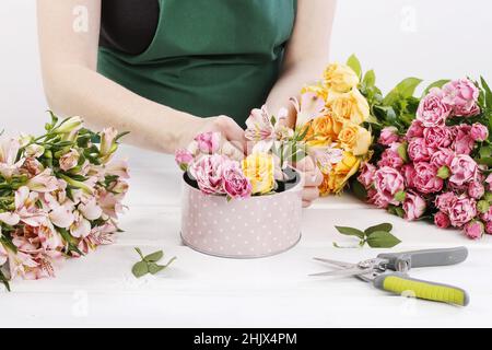 Floristin bei der Arbeit: Frau zeigt, wie man Blumenarrangement mit Rosen und anderen Blumen in einer rosa gepunkteten Dose zu machen. Schritt für Schritt, Tutorial. Stockfoto