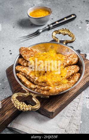Crepes Suzette - Pfannkuchen mit Orangensauce in einer Pfanne. Grauer Hintergrund. Draufsicht Stockfoto