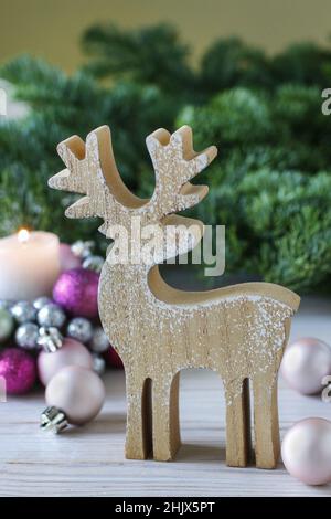 Hölzerne Hirschfigur auf dem Hintergrund von Tannenzweigen. Festliche Einrichtung Stockfoto