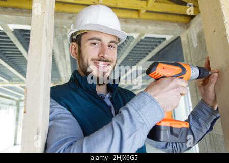 Junger Baumeister mit einer Akku-Bohrmaschine Stockfoto