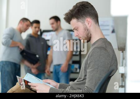 Junger Mann beim Lesen der Zeitschrift im Warteraum Stockfoto