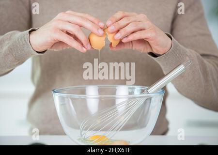 Hände halten eine Schüssel, bevor Eier geschlagen werden Stockfoto