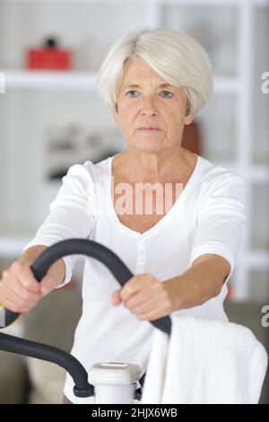 Attraktive ältere Frau im Fitnessclub, die auf dem Stepper trainiert Stockfoto