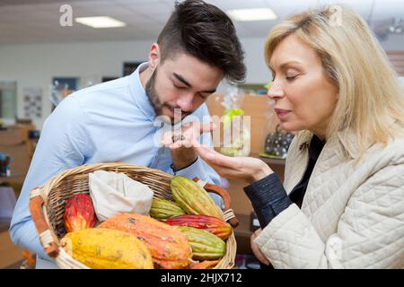 Lebensmittelhändler und Kunden riechen exotische Früchte Stockfoto