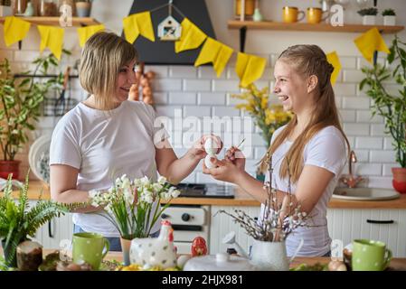 Mutter und Tochter bereiten sich auf Ostern vor, indem sie die Stärke der Eier überprüfen. Stockfoto