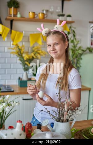 Ein junges Mädchen im Alter von 12 Jahren malt ein Ei für Ostern. Stockfoto