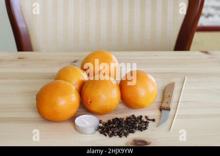 Frau zeigt, wie man Orangenpomander Ball mit Kerze - Schritt für Schritt, Tutorial. Stockfoto