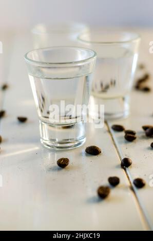 Sambuca in Schnapsgläsern und Kaffeebohnen auf weißem Hintergrund Stockfoto