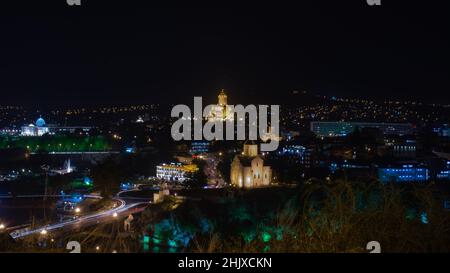 Schöne nächtliche Landschaft der Stadt Tiflis mit seinen prominenten Wahrzeichen, die im Dunkeln beleuchtet sind. Nachtansicht der Stadtlandschaft. Stockfoto