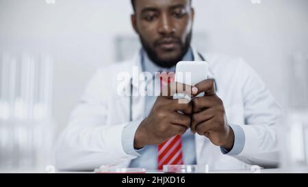 Verschwommene afroamerikanische Ärztin auf dem Smartphone Stockfoto