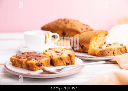 Hausgemachter Kuchen mit Rosinen, Mandeln, weichem Karamell auf weißem und rosafarbenem Hintergrund. Seitenansicht, Nahaufnahme, selektiver Fokus. Stockfoto