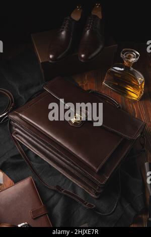Schultertasche aus Leder für Männer mit Armbanduhr, Paar schwarze Lederschuhe für Männer und Notizbuch Stockfoto