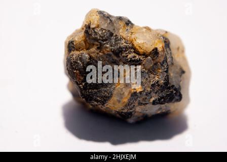 Kleiner Quarzstein mit schwarzem Biotit auf weißem Hintergrund Stockfoto