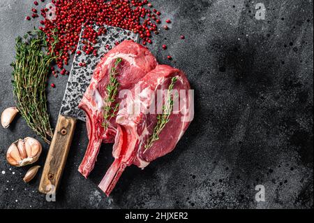 Rohe Tomahawk Rib Kalbssteaks auf Fleischspalter. Schwarzer Hintergrund. Draufsicht. Speicherplatz kopieren Stockfoto
