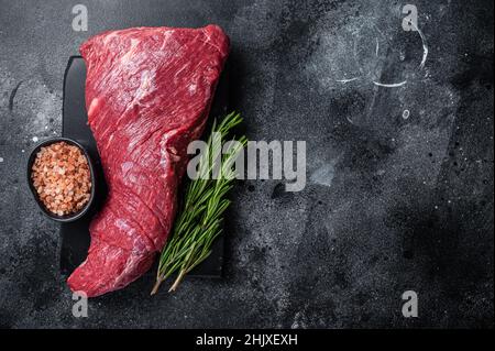 Rohes amerikanisches Tri Tip Beef Steak auf Marmorplatte. Schwarzer Hintergrund. Draufsicht. Speicherplatz kopieren Stockfoto