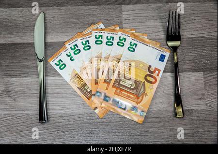 50-Euro-Banknoten mit Gabel und Gabel auf Holzfläche Stockfoto