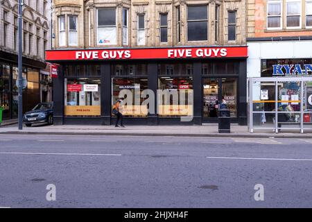 Leeds UK, 31st. Januar 2022: Foto des Leeds City Centre zeigt das berühmte Restaurant Five Guys in der Stadt mit Menschen und Verkehr, die an der Ame vorbeiziehen Stockfoto
