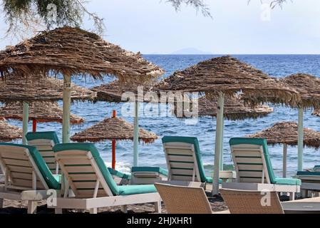 Liegestühle und Sonnenschirme am Perissa Strand, Santorini Stockfoto