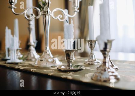 Auf dem Tisch stehen viele Kerzen in Kerzenständern. Candlelight Party. Stockfoto