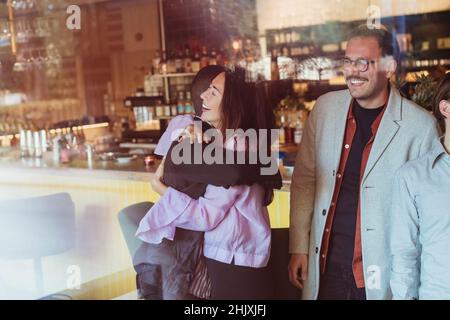 Glückliche weibliche und männliche Freunde umarmen während der Party im Restaurant Stockfoto