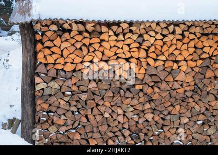 Feuerholz Lager auf dem Land. Brennholz für den Winter. Brennholz im Freien Lagerung, überdachte Holzstämme gestapelt. Stockfoto