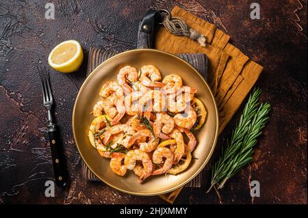 Würzige Knoblauch-Chili-Garnelen Shrimps mit Zitrone und Rosmarin auf einem Teller. Dunkler Hintergrund. Draufsicht Stockfoto