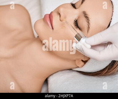 Weibliche Patientin mit geschlossenen Augen genießt kosmetologische Verfahren mit Behandlungen Öle und Serum Gesichtshaut Pflege Stockfoto