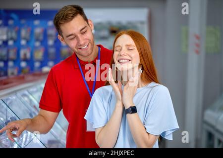 Pretty Redhead Lady In Casual Wear Stand By Regalen Mit Smartphones Im Geschäft, Mit Consultant, Nette Kundin Woman Träumt Über New Modern Mobil Stockfoto