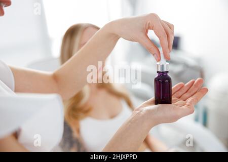 Weibliche Kosmetikerin Hände halten Flasche Vitamin-Serum Stockfoto