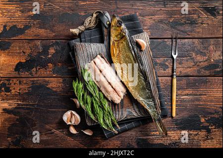 Duftendes geräuchertes Heringsfischfilet auf Holzbrett mit Kräutern. Holzhintergrund. Draufsicht Stockfoto