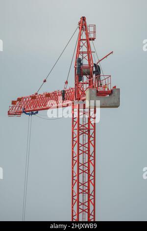 Professioneller Kranführer, der den Kran in großer Höhe inspiziert, Konzept für gefährliche Arbeiten Stockfoto