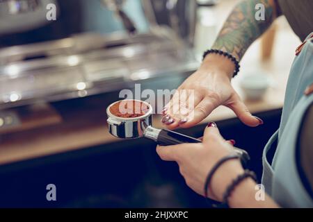 Weibliche Barista Hände halten einen Portafilter mit frischem Kaffee Stockfoto