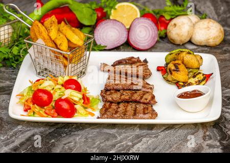 Gegrilltes Rinderfilet-Steak auf einer Keramikplatte mit Butter und Thymian. Filet Mignon Rezept mit Gemüse Stockfoto