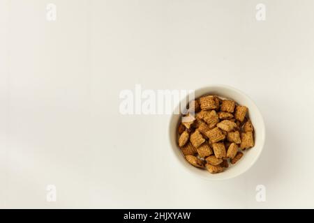 Schüssel mit Müsli auf weißem Hintergrund. Leckeres Frühstück mit Flocken in einer weißen Keramikschale serviert Stockfoto