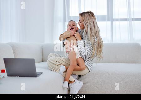 Niedlichen kleinen Jungen und kuscheln aufgeregt junge Mutter zeigen Liebe und Zuneigung, lächelnde Mutter und lustige kleine Vorschulkinder Sohn haben Spaß zu Hause umarmen teilen Stockfoto