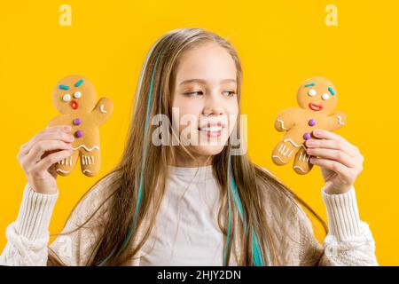 Lustiger Teenager. Ein süßes Mädchen hält in ihren Händen zwei Kekse in Form eines Mannes. Schuljunge. Stockfoto