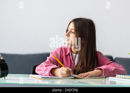 Unglücklich kleines kaukasisches Mädchen Kind sitzen am Tisch zu Hause fühlen faul unmotiviert Hausaufgaben zu machen. Bildungskonzept. Stockfoto