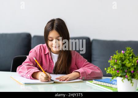 Unglücklich kleines kaukasisches Mädchen Kind sitzen am Tisch zu Hause fühlen faul unmotiviert Hausaufgaben zu machen. Bildungskonzept. Stockfoto