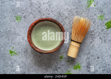 Matcha grüner Tee in einer handgefertigten Schüssel mit einem Bambusbesen. Stockfoto