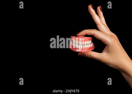 Der Zahnarzt hält Prothesen in den Händen. Zahnprothese in den Händen des Arztes Nahaufnahme. Vorderansicht der kompletten Prothese. Prothetische Zähne Stockfoto