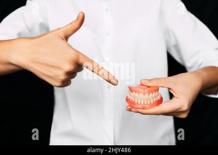 Der Zahnarzt hält Prothesen in den Händen. Zahnprothese in den Händen des Arztes Nahaufnahme. Vorderansicht der kompletten Prothese. Zahnmedizin Konzept Stockfoto