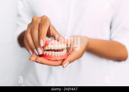 Der Zahnarzt hält Prothesen in den Händen. Zahnprothese in den Händen des Arztes Nahaufnahme. Vorderansicht der kompletten Prothese. Zahnmedizin Konzept Stockfoto