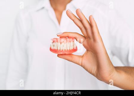 Der Zahnarzt hält Prothesen in den Händen. Zahnprothese in den Händen des Arztes Nahaufnahme. Vorderansicht der kompletten Prothese. Zahnmedizin Konzept Stockfoto