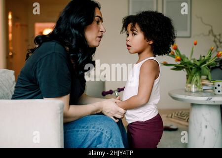 Mutter spricht mit Tochter im Wohnzimmer zu Hause Stockfoto