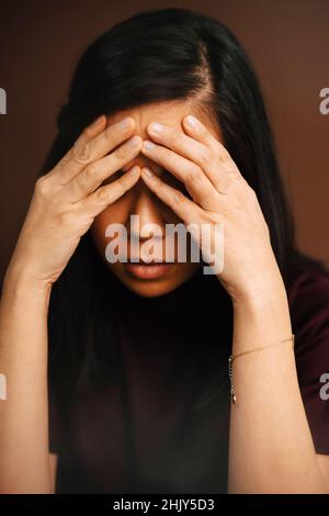 Frustrierte Frau mit Kopf in den Händen im Studio Stockfoto