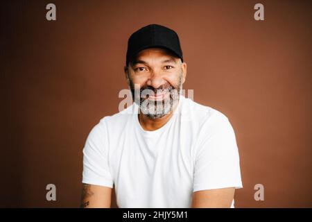 Porträt eines selbstbewussten Mannes mit Hut vor braunem Hintergrund Stockfoto