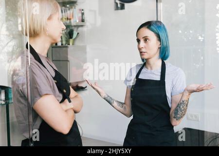 Weibliche Besitzerin im Friseursalon im Gespräch mit einer Mitarbeiterin Stockfoto